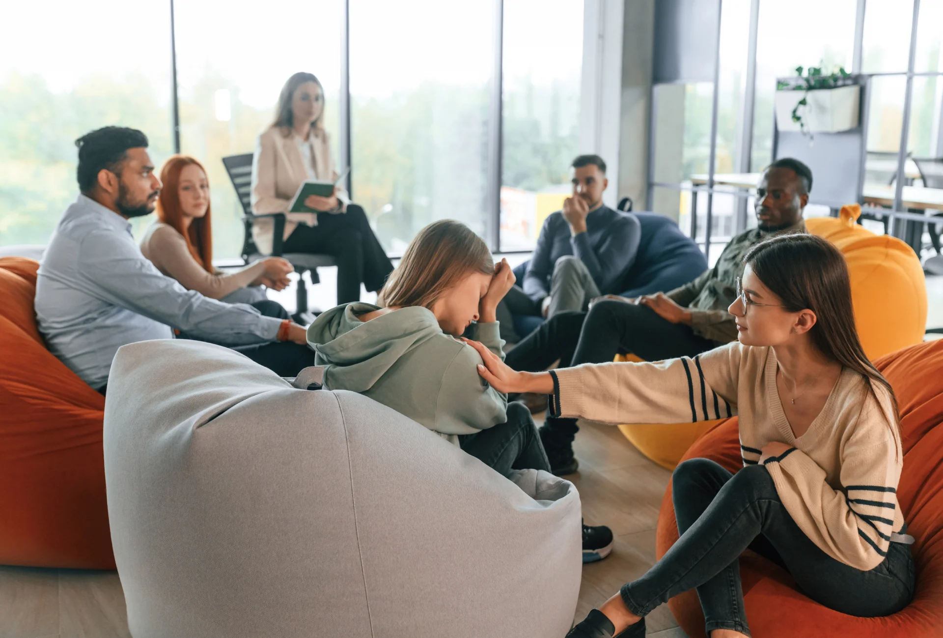 Group therapy session in a supportive sober living environment, featuring diverse individuals seated on bean bags, engaged in conversation and emotional support at Goldfinch Residences.